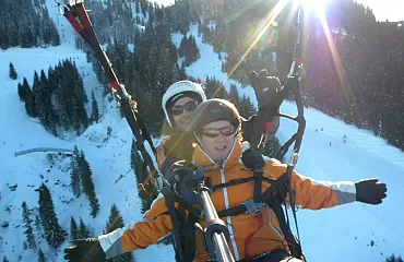 Frau mit Guide beim Tandemparagleiten im Winter