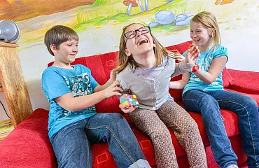Spass bei der Kinderbetreuung. Mädchen wird gekitzelt und lacht dabei.